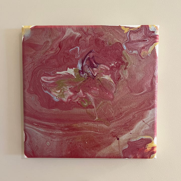 Two small paintings made using poured acrylic paint. One is mostly red and the other is mostly blue.