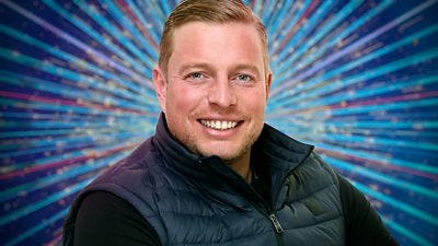 A head and shoulders shot of Thomas Skinner in a dark body warmer over a dark top, smiling to camera. He's set against a glittering blue background.