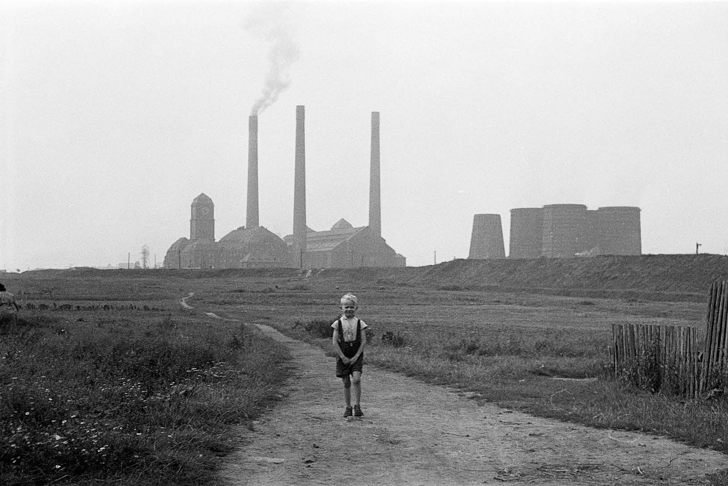 A boy walks near a heat power station in Bytom, Poland, circa 1960. Photo by Zofia Rydet.