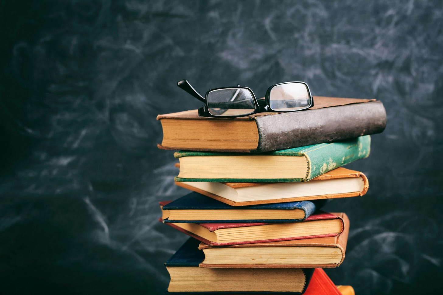 A stack of books with a pair of eyeglasses resting on top