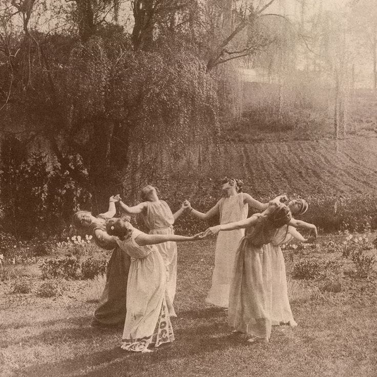 This may contain: four women in long dresses are holding hands and pulling on a rope with their arms
