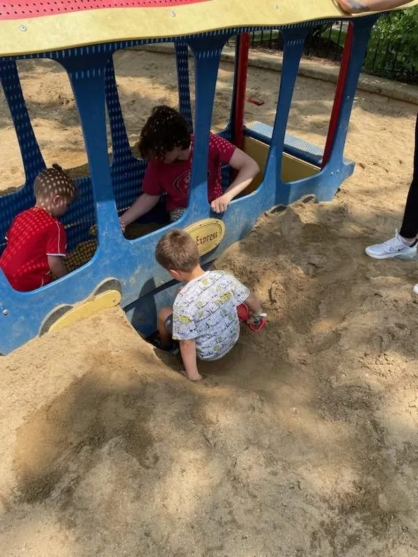 3 boys sonsentrating on building in a sand box (writing about moments in time)