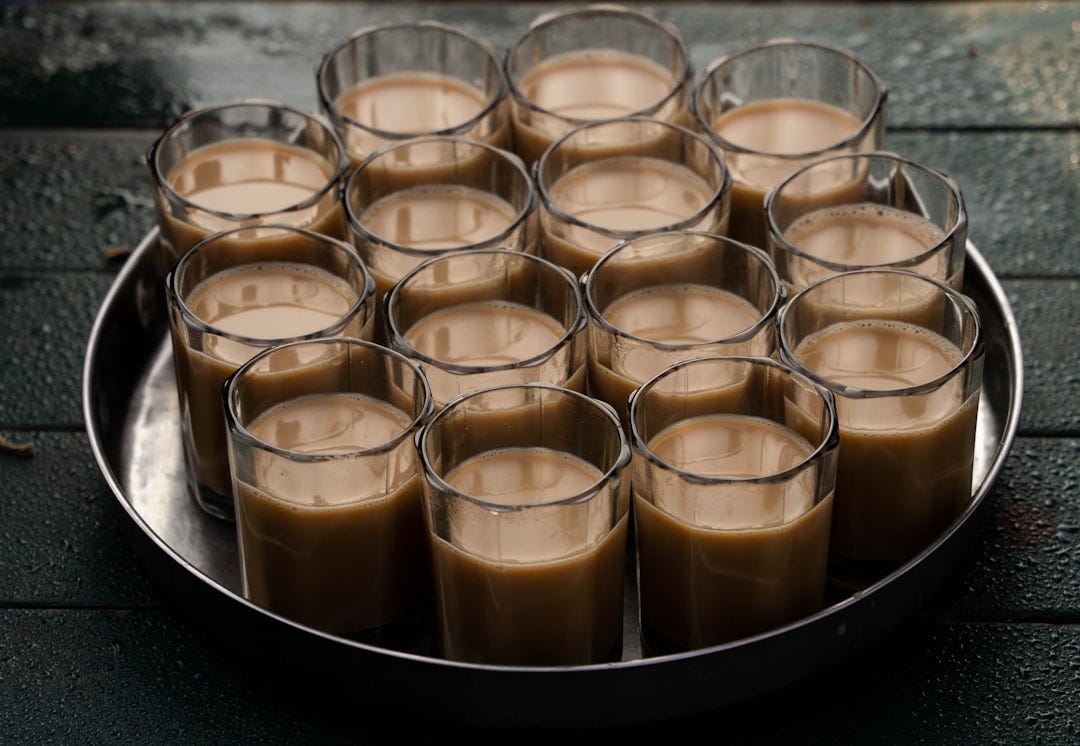 A metal tray filled with glasses filled with liquid A metal tray filled with glasses filled with liquid