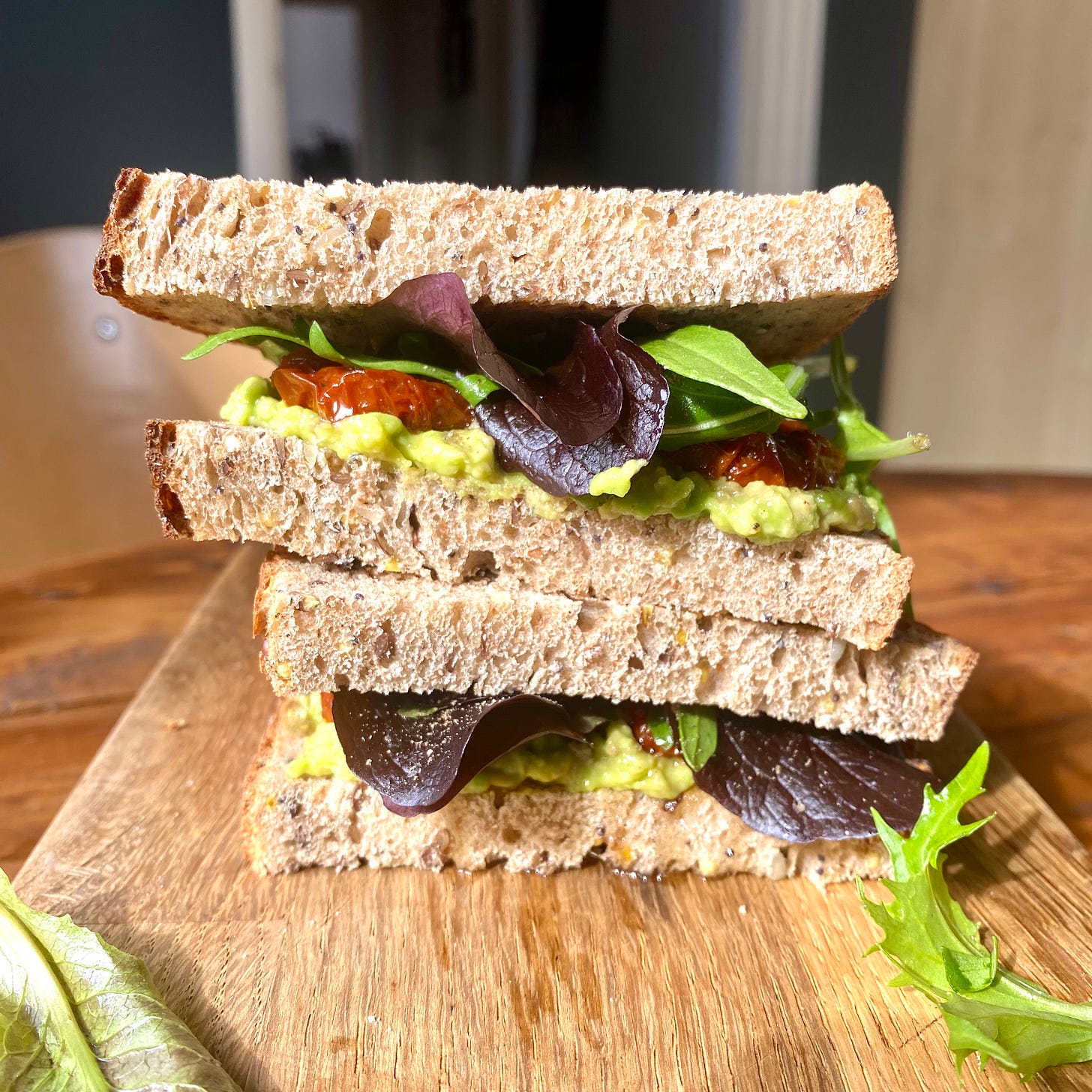 Cross section of a seeded sourdough sandwich filled with avocado, salad and sun-dried tomato 