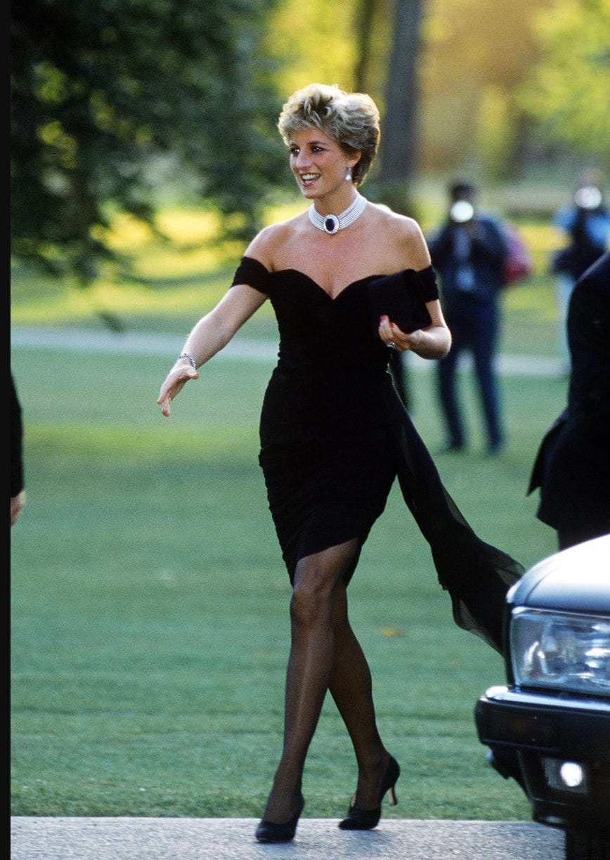 Princess Diana in her infamous revenge dress, a black mini, off the shoulder, tight dress featuring black tights and a pearl choker. 