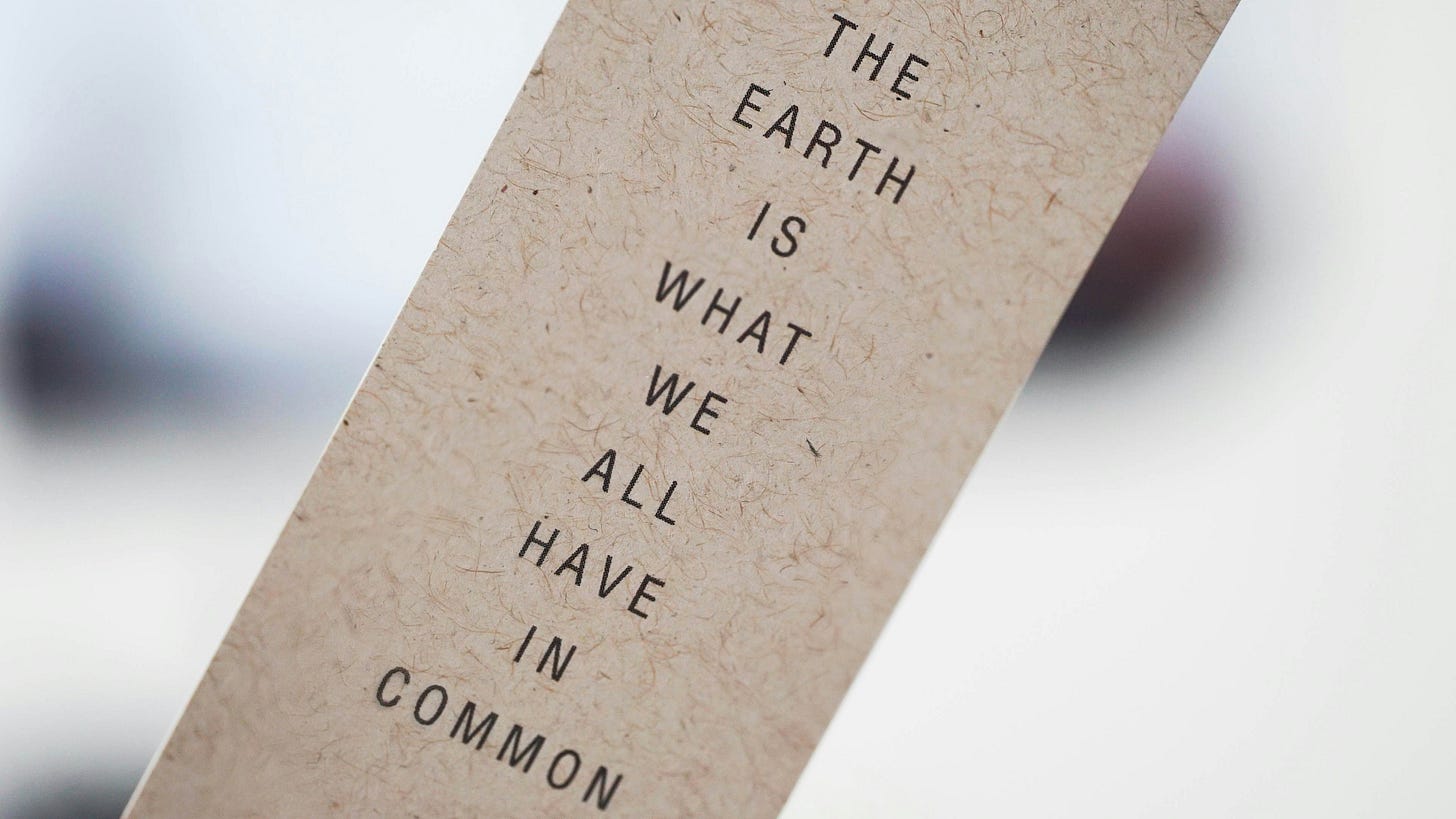 Close-up of what may be a bookmark and printed down the front is: THE EARTH IS WHAT WE ALL HAVE IN COMMON.