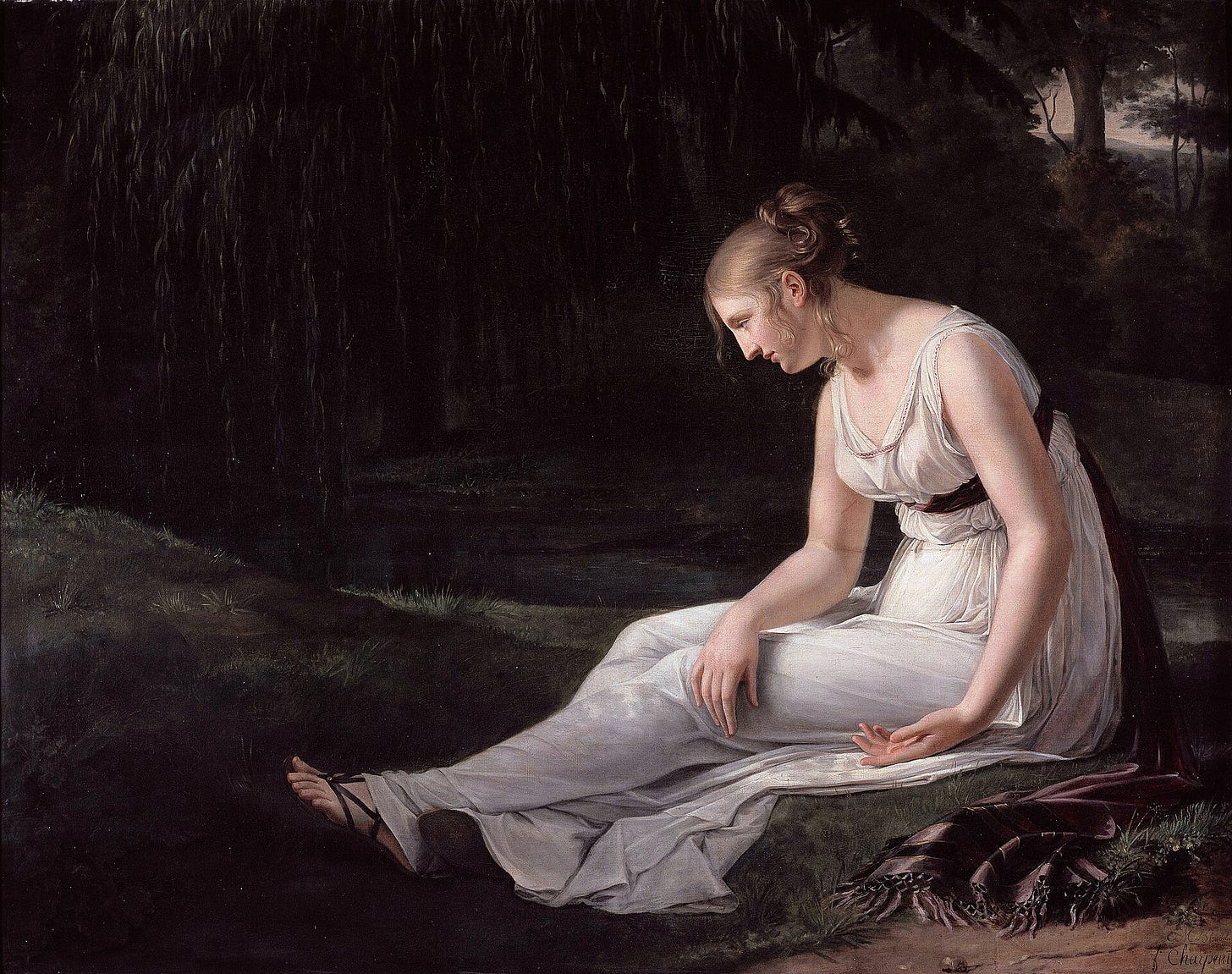 A young woman in a white antique-style dress sits alone by a stream in a dark wood, her head lowered, her hands loosely clasped in her lap.