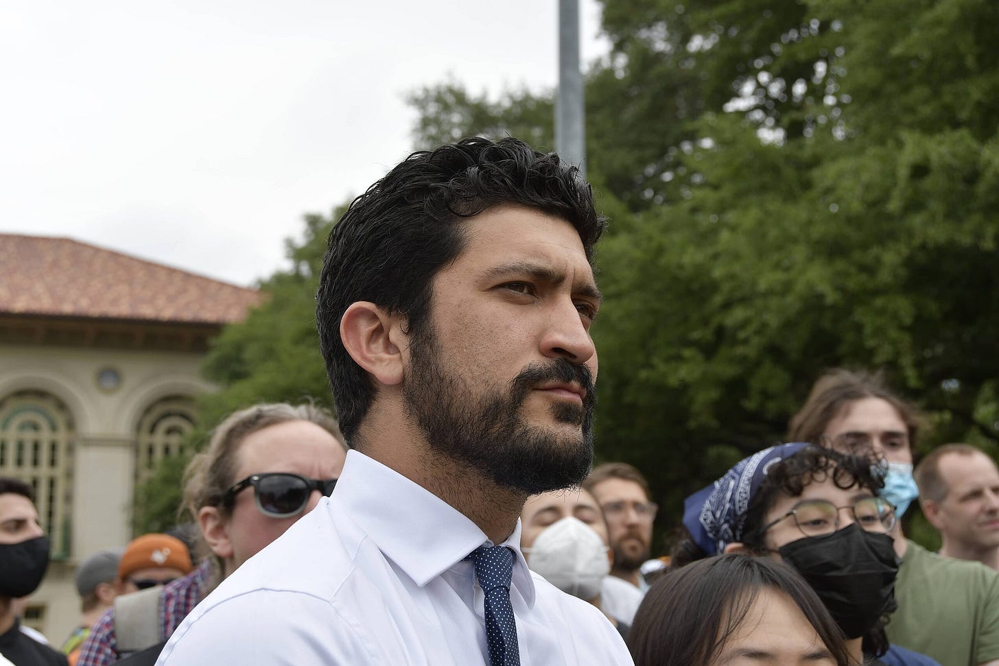 Casar appears with well-kept hair slicked back, a carefully maintained beard and mustache, and dark brown eyes as he looks intently towards the viewer's right, in the direction of the protest leaders. It is clear he is listening intently to the speaker's every word. Soon after this photo was taken, he will speak to the crowd as well. In the background are pro-Palestine and pro-Israel demonstrators, who attempt to yell over one another to communicate their disparate views. Many pro-Palestine demonstrators sport masks and sunglasses to hide their identities. Casar appears with well-kept hair slicked back, a carefully maintained beard and mustache, and dark brown eyes as he looks intently towards the viewer's right, in the direction of the protest leaders. It is clear he is listening intently to the speaker's every word. Soon after this photo was taken, he will speak to the crowd as well. In the background are pro-Palestine and pro-Israel demonstrators, who attempt to yell over one another to communicate their disparate views. Many pro-Palestine demonstrators sport masks and sunglasses to hide their identities.
