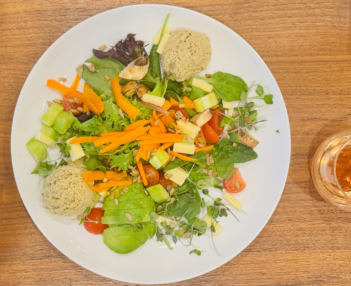 Jan's Health Bar Classic Salad with Vegetarian Turkey, Avocado, Mixed greens, white cheddar cheese, sunflower seeds, cucumber, tomato, carrots, mushrooms, sprouts and Herby Vinaigrette and a glass of Inman Family wines, Endless Crush® Rosé of Pinot Noir, served at the table.