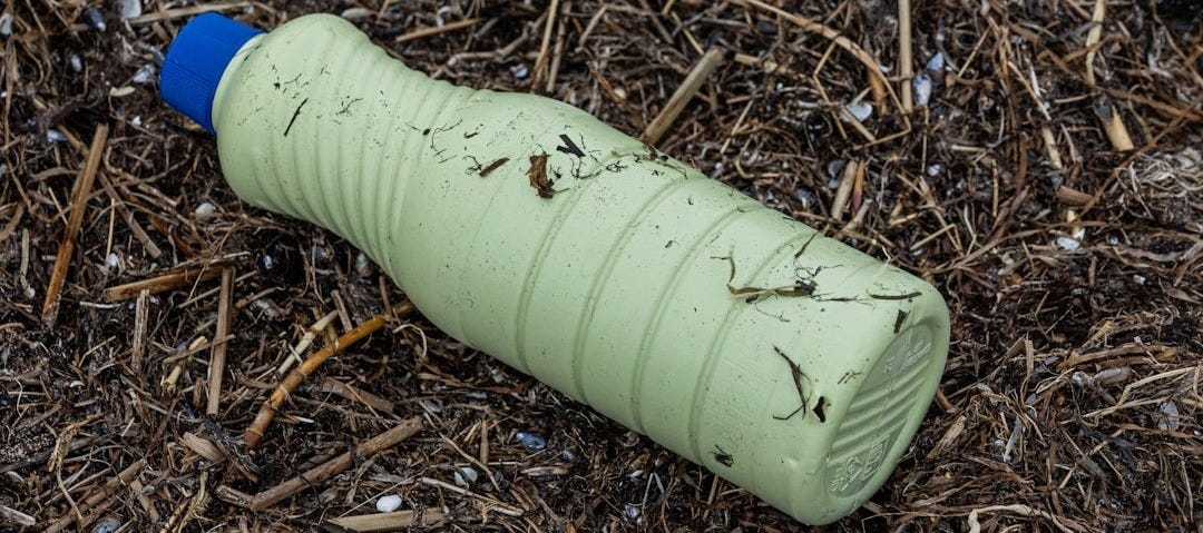 a green plastic bottle laying on the ground