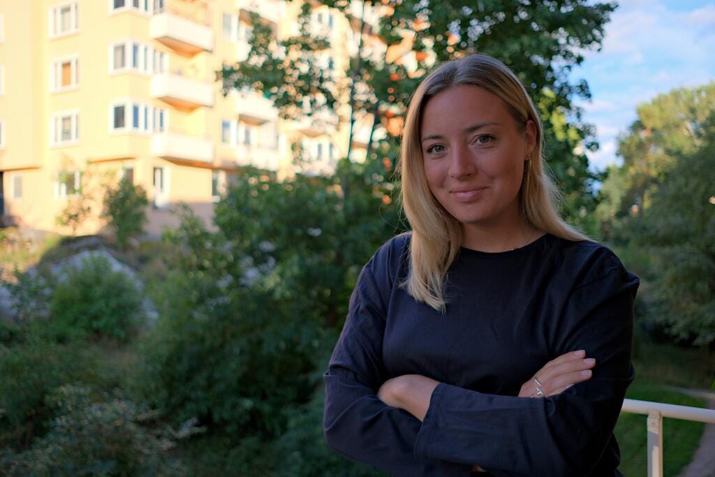 Amelie Reuterskiöld i svart tröja mot grönskande bakgrund