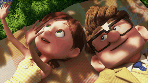 Gif con i giovani Ellie e Carl, personaggi del film Pixar Up, sono sdraiati su una coperta da picnic. Ellie, a sinistra, sorride con una mano alzata come per coprirsi dal sole, mentre guarda verso l'alto. Carl, a destra con gli occhiali, la guarda affettuosamente.