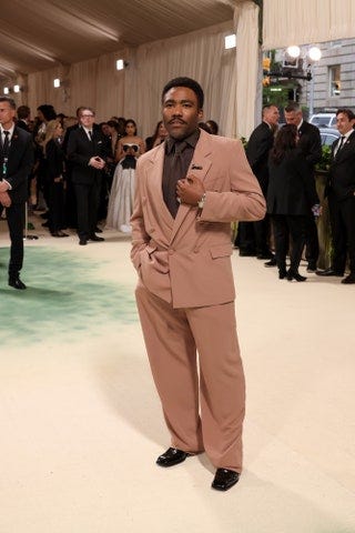 Image may contain Donald Glover Clothing Formal Wear Suit Adult Person Standing Wristwatch Footwear and Shoe