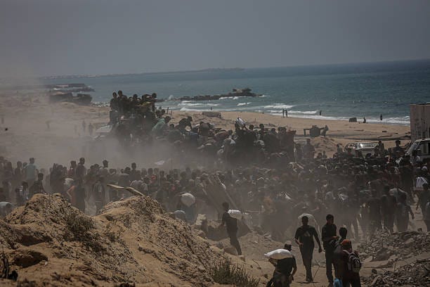 Palestinians walk for kilometers after receiving flour aid distributed from trucks that entered the Zikim area, a kibbutz in southern Israel, amid...