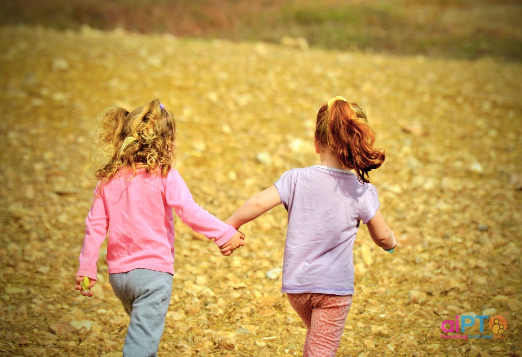 two little girls walking hand in hand in the outdoors. Picture taken from behind two little girls walking hand in hand in the outdoors. Picture taken from behind