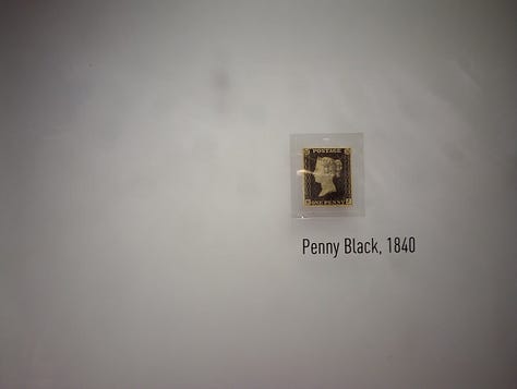 Left: Stamp featuring head of Queen Victoria, Middle, display with enlarged Penny Black Stamp, portrait of Rowland Hill and text Right, photo of Rowland Hill and text