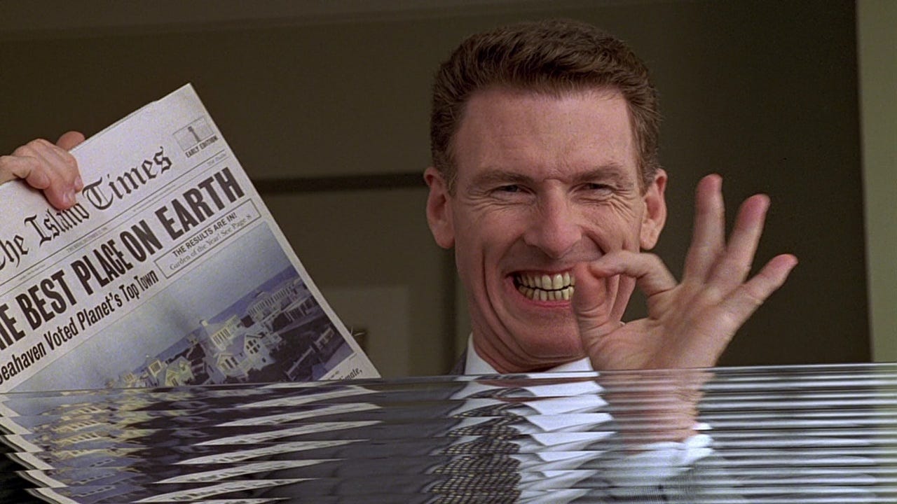 A smiling man holds up a newspaper with the headline “The Best Place on Earth,” his exaggerated grin appearing unsettling as he looks directly toward the viewer.