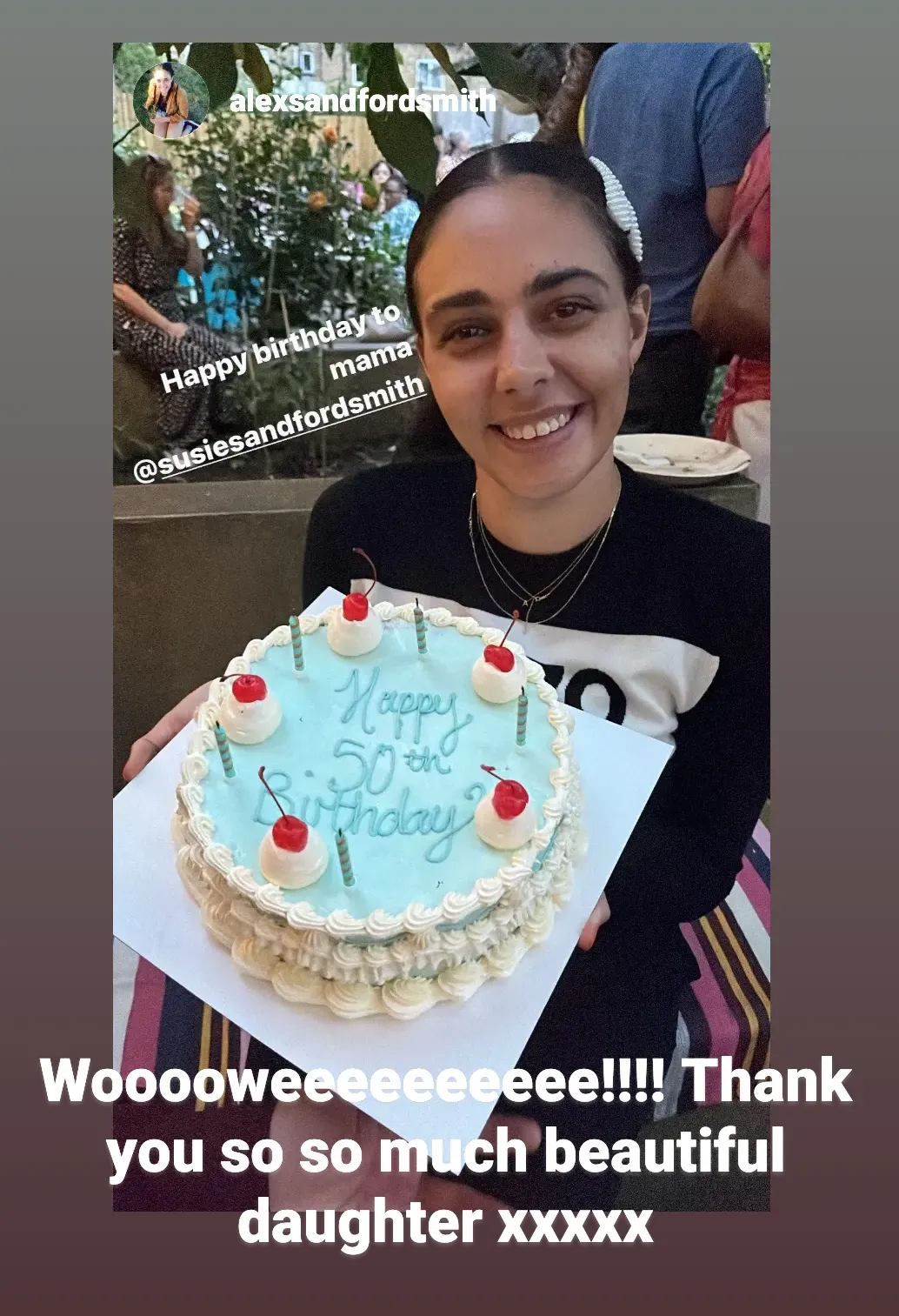 A gorgeous young woman sitting in a garden holding a decadently iced birthday cake the photo is a screenshot from an Instagram story