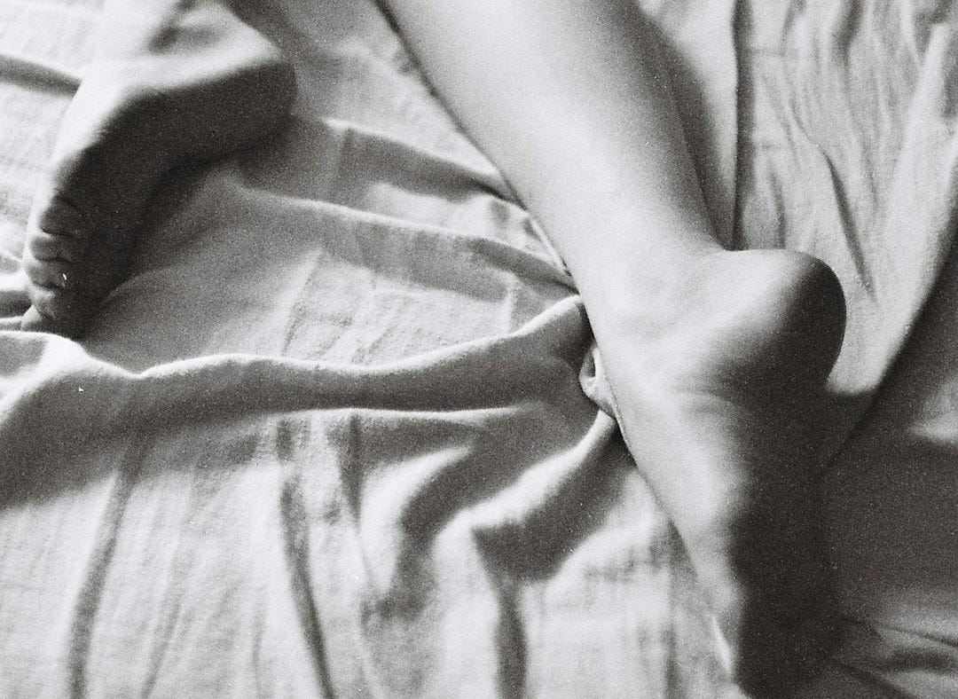 grayscale photo of woman lying on bed