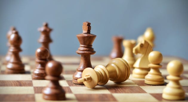Last move in chess, check mate, white king lying down defeated, defocused backdrop Last move in chess, check mate, white king lying down defeated, defocused backdrop