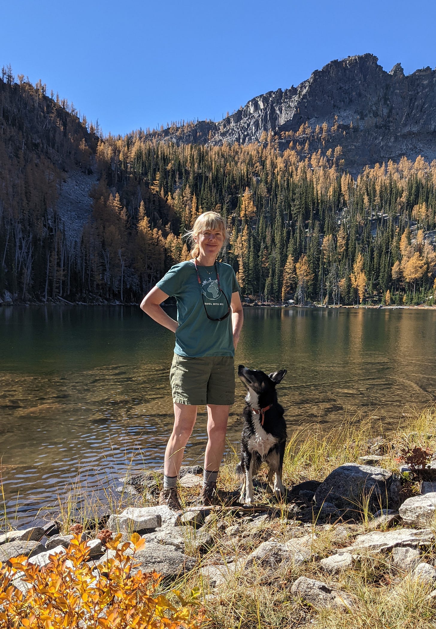 Writer & dog standing at the shore of a high alpine lake in the Bitterroot Mountains of Montana