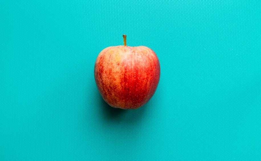 red apple fruit on blue surface