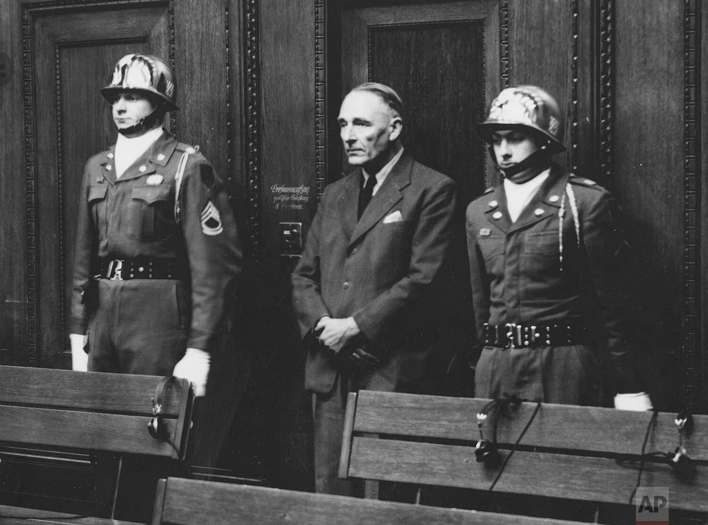 Dr. Ernst Woermann is sentenced to 7 years imprisonment, escorted by U.S. Army honor guards Sgt. Thomas H. Andress and Pfc. Ciro J. Ruggero of the 16th Infantry, during the Nuremberg trials.