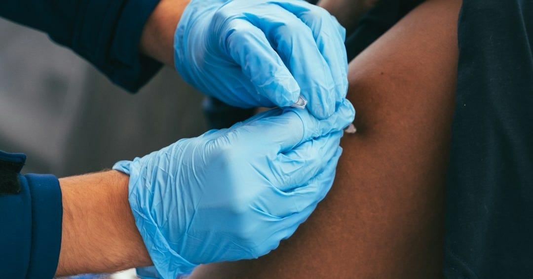 a person in blue gloves is getting a vaccium