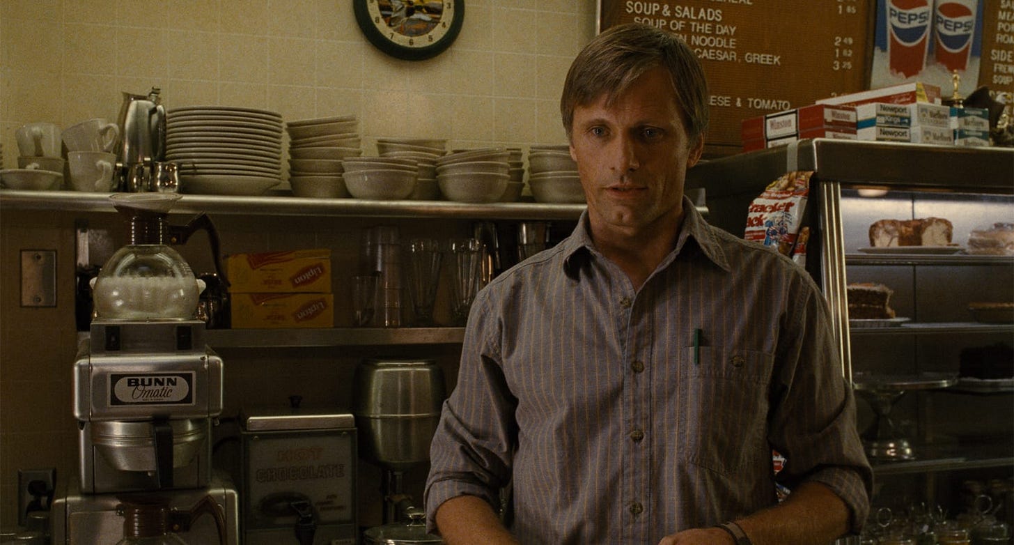 A History of Violence | Still features Viggo Mortensen as Tom Stall behind a coffee counter.