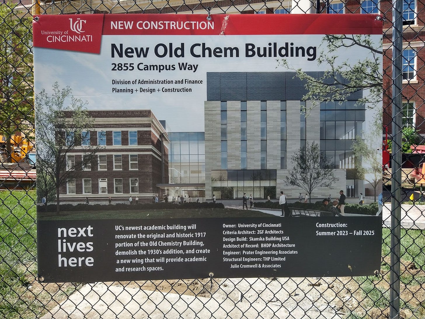 Sign on a chainlink fence depicting a rendering of the New Old Chem Building and information about the constructin project.