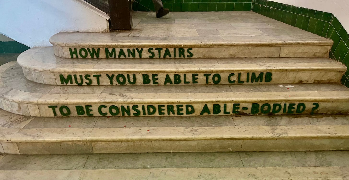 Marble steps at the Old GMC Complex in Goa with green embossed words in uppercase: How many stairs must you be able to climb to be considered able-bodied? 