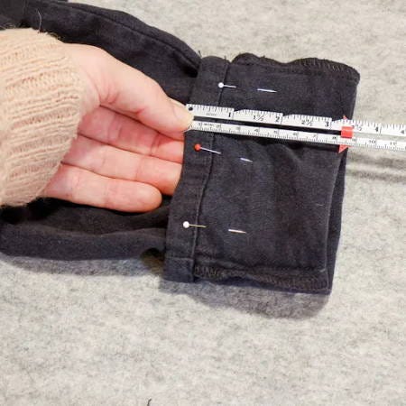 measuring how much pants should be shortened with a measuring gauge, pins to hold the hem