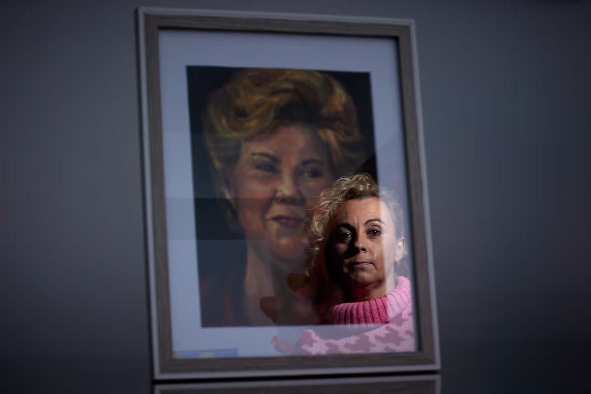 Un riflesso del volto di una donna in un maglione rosa si sovrappone a un ritratto incorniciato di una donna bionda. Un riflesso del volto di una donna in un maglione rosa si sovrappone a un ritratto incorniciato di una donna bionda.