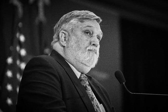 a black and white photo of Doug Wilson in front of a microphone a black and white photo of Doug Wilson in front of a microphone