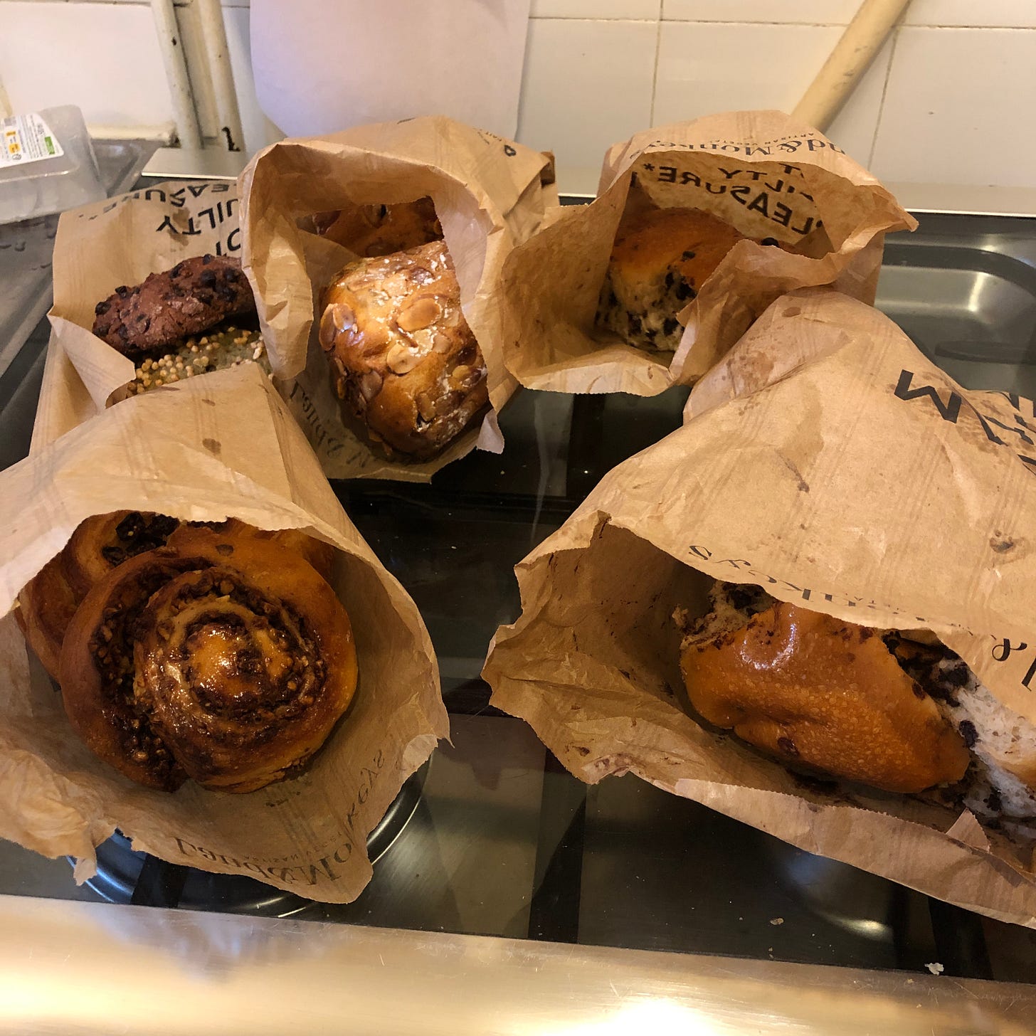 Photo de sacs en papier dans lesquels on voit des brioches, babka, kouglofs, pain aux raisins, moonbread, etc. Photo de sacs en papier dans lesquels on voit des brioches, babka, kouglofs, pain aux raisins, moonbread, etc.