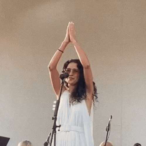 a woman in a white dress singing into a microphone