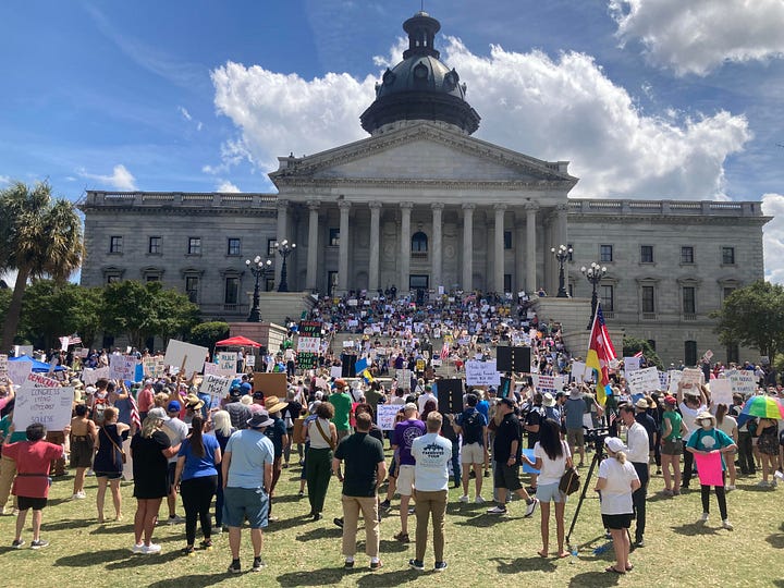 From top left - someone holds a sign saying "Billionaires are the only dangerous minority" in front of a truck with an upside down US flag; a large crowd carrying signs fills the lawn in front of a government building; a large group of people holding signs line a sidewalk; a large group of people with signs gather in a park, in the foreground is a sign that reads "Love is greater than fear" and an American flag.