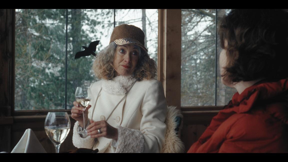 A seated womanin a white winter coat looks sceptically at a woman in a red coat