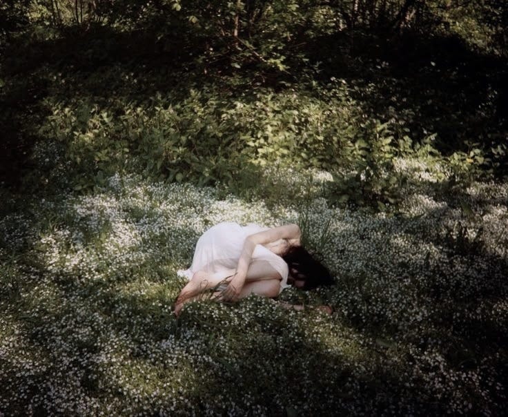 This may contain: a woman laying in the grass with her head down This may contain: a woman laying in the grass with her head down