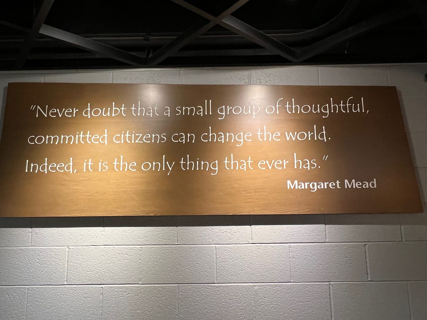 A sign that says “Never doubt that a small group of thoughtful, committed citizens can change the world. Indeed, it is the only thing that ever has.” -Margaret Mead