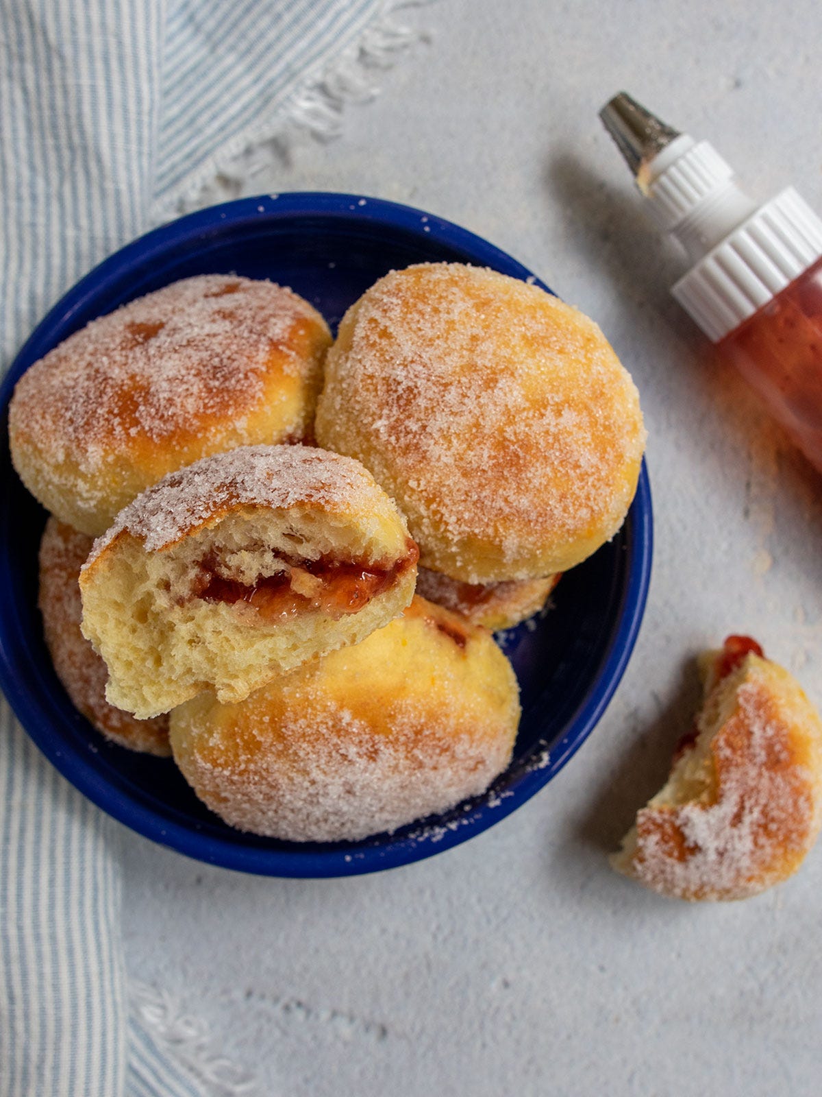 Baked donuts in a blue bowl with a squirt bottle of jam nearby. Baked donuts in a blue bowl with a squirt bottle of jam nearby.