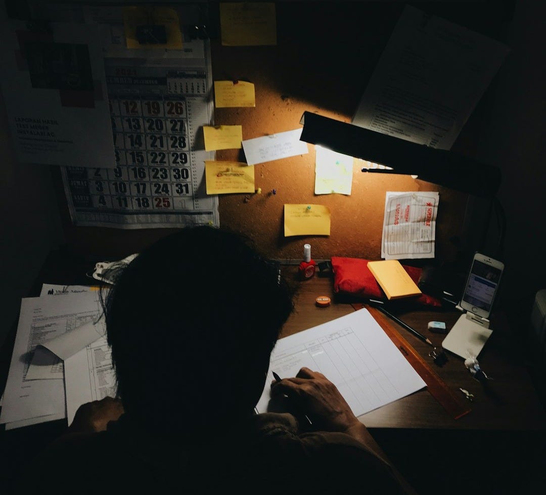 a person sitting at a desk in front of a lamp