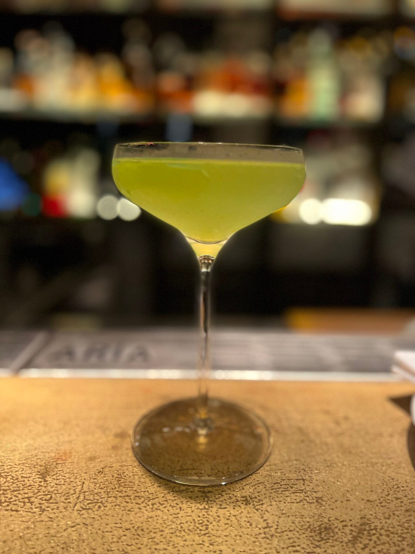 Ein schöner Drink mit gelblich grüner Farbe in einem eleganten Glas, das beschlagen ist Ein schöner Drink mit gelblich grüner Farbe in einem eleganten Glas, das beschlagen ist