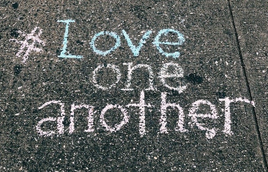 love one another chalk written on concrete floor