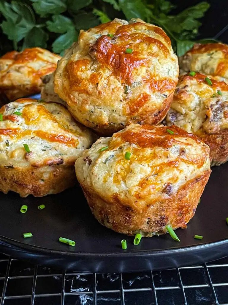 Sausage muffins stacked on a black plate garnished with diced chives. Sausage muffins stacked on a black plate garnished with diced chives.