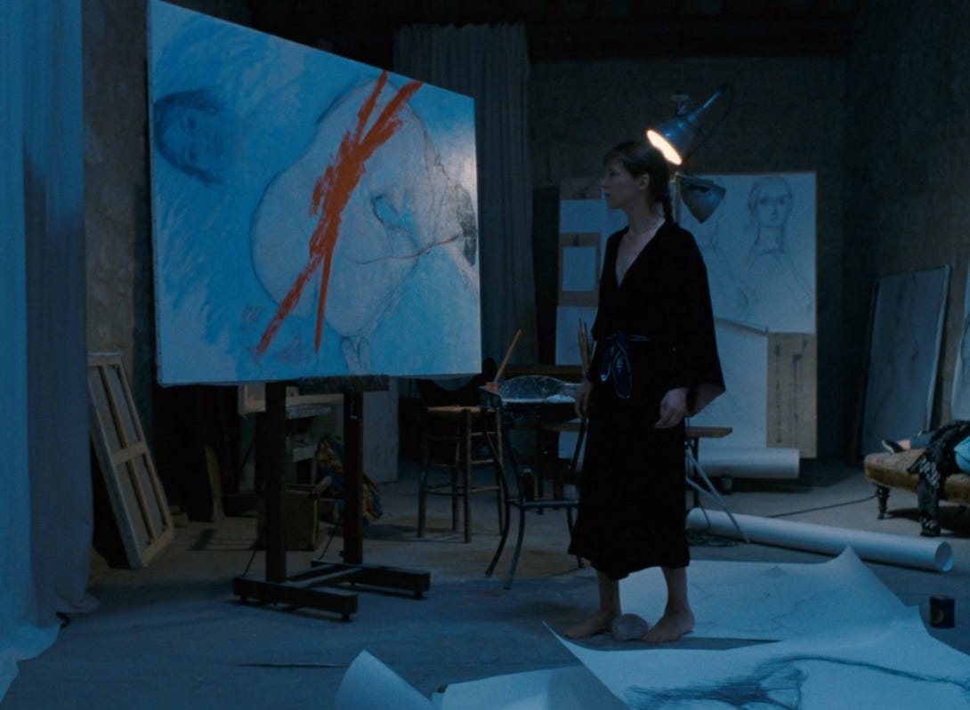 Movie still from La Belle Noiseuse. A woman stands in front of a painting with a red streak across it.