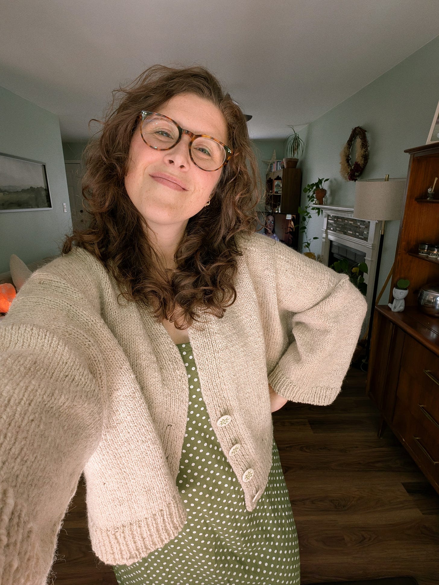 a girl taking selfie in a cardigan and a green polkadot dress