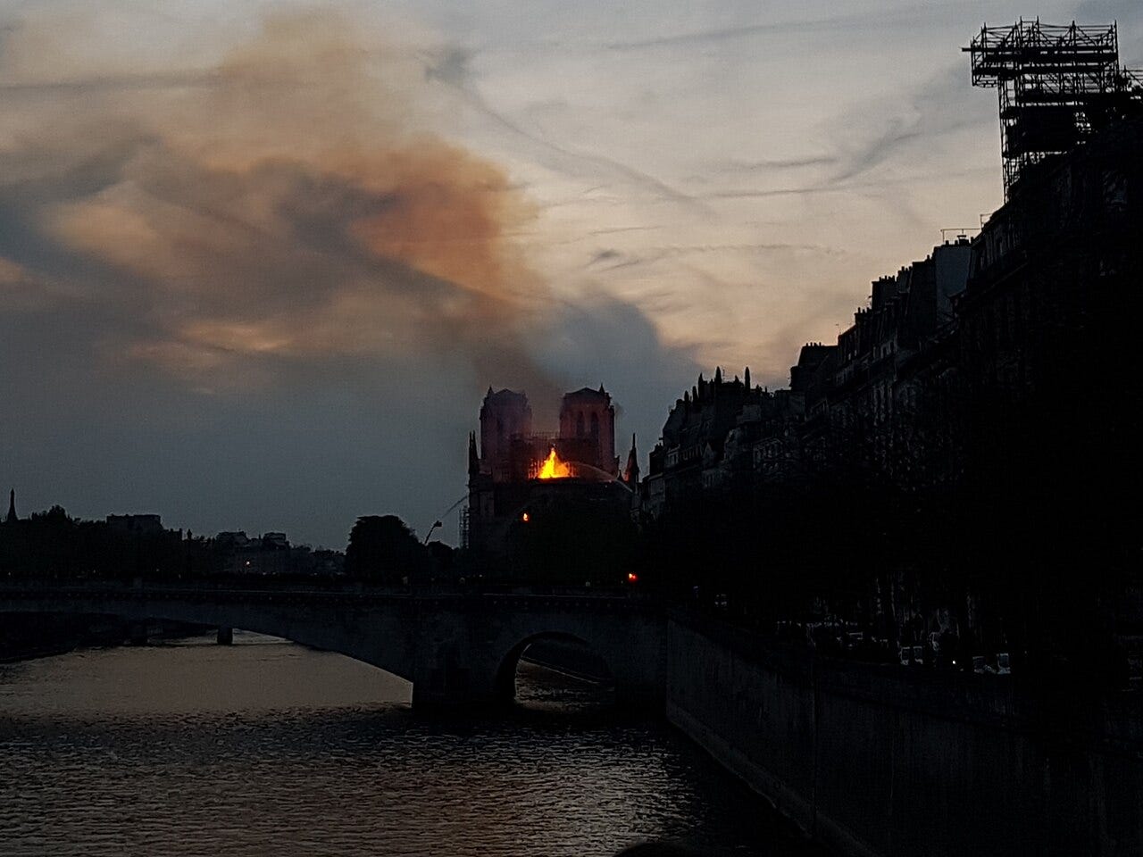 Night view of Notre-Dame glowing orange over the Seine