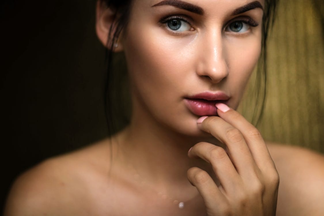 Free Close-up portrait capturing a woman's natural beauty with soft lighting and a thoughtful expression. Stock Photo