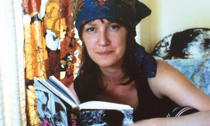 This may contain: a woman is reading a book while sitting on a bed with her head turned to the side